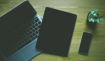 Flat lay of laptop, tablet, and smartphone on wooden desk