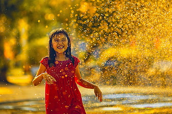 Happy Girl Playing in Golden Water Spray