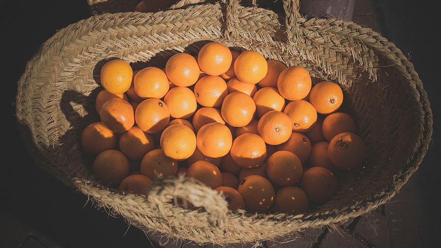 Top View of Fresh Oranges in Woven Straw Basket