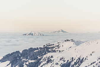 Snowy mountain peaks above sea of clouds with ski resort
