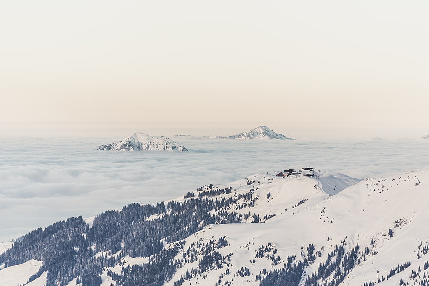 Snowy mountain peaks above sea of clouds with ski resort