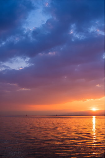 Dramatic Sunset Over Calm Ocean with Sailboats