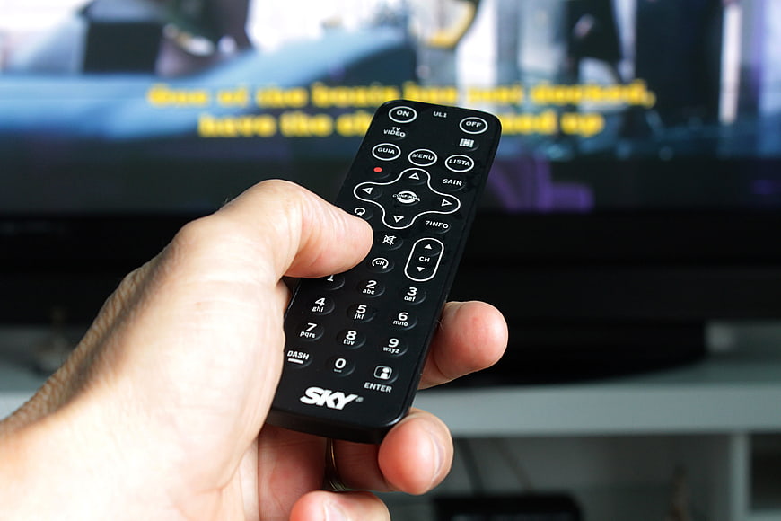Hand holding Sky remote control pointing at TV