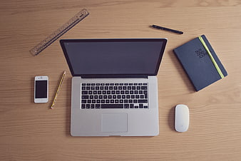 Flat lay of laptop, notebook, and office supplies on wooden desk