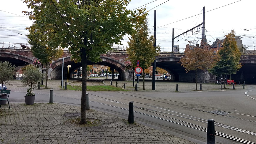 Urban tram tracks leading to brick railway bridge in autumn