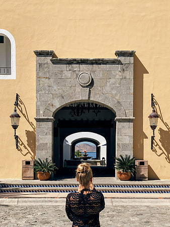 Woman Viewing Ocean Through Symmetrical Stone Archway