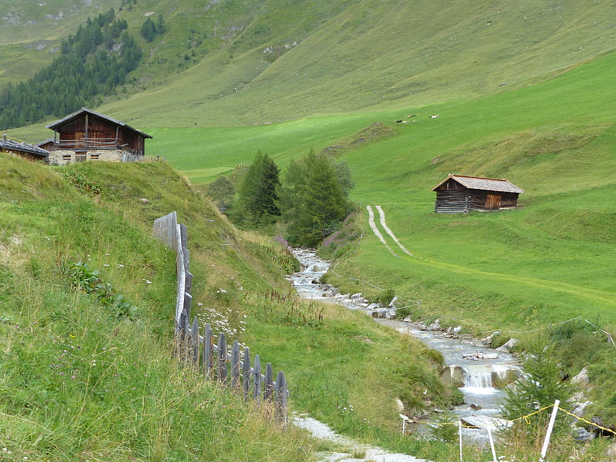 Alpine landscape with wooden chalets and stream in South Tyrol