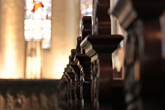 Close-up of wooden church pews with stained glass window background