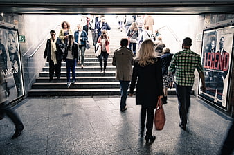 Crowd of people walking up stairs in urban subway station