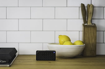 Black Bluetooth Speaker on Wooden Kitchen Counter with Lemons