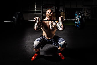 Tattooed Man Performing Heavy Barbell Squat in Dark Gym