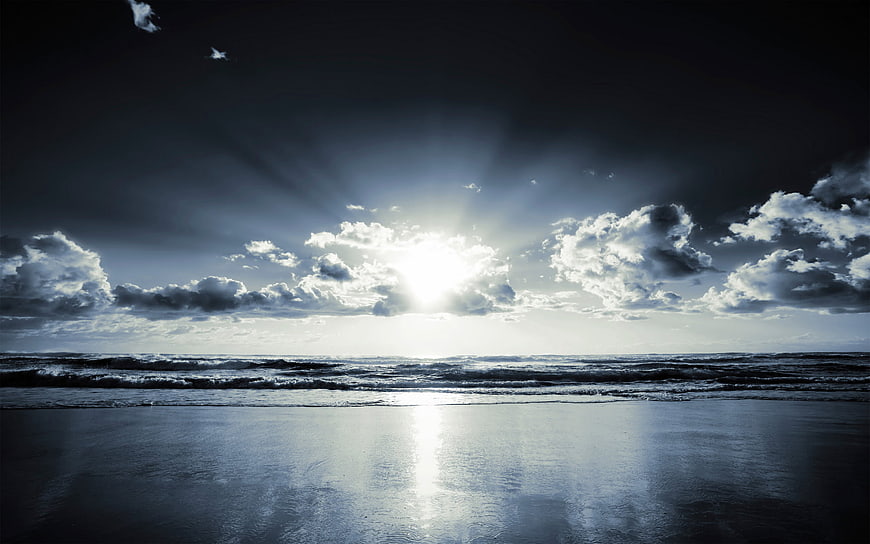 Dramatic Sun Rays Breaking Through Clouds Over Ocean Waves