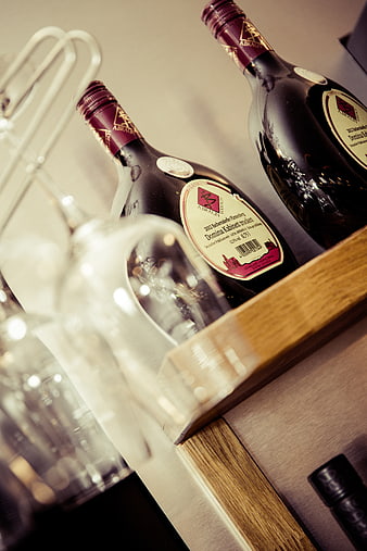 Close-up of wine bottles and glasses on a wooden shelf
