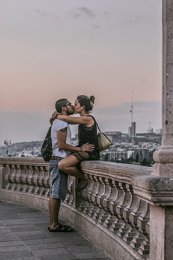 Romantic couple kissing on a stone bridge at sunset