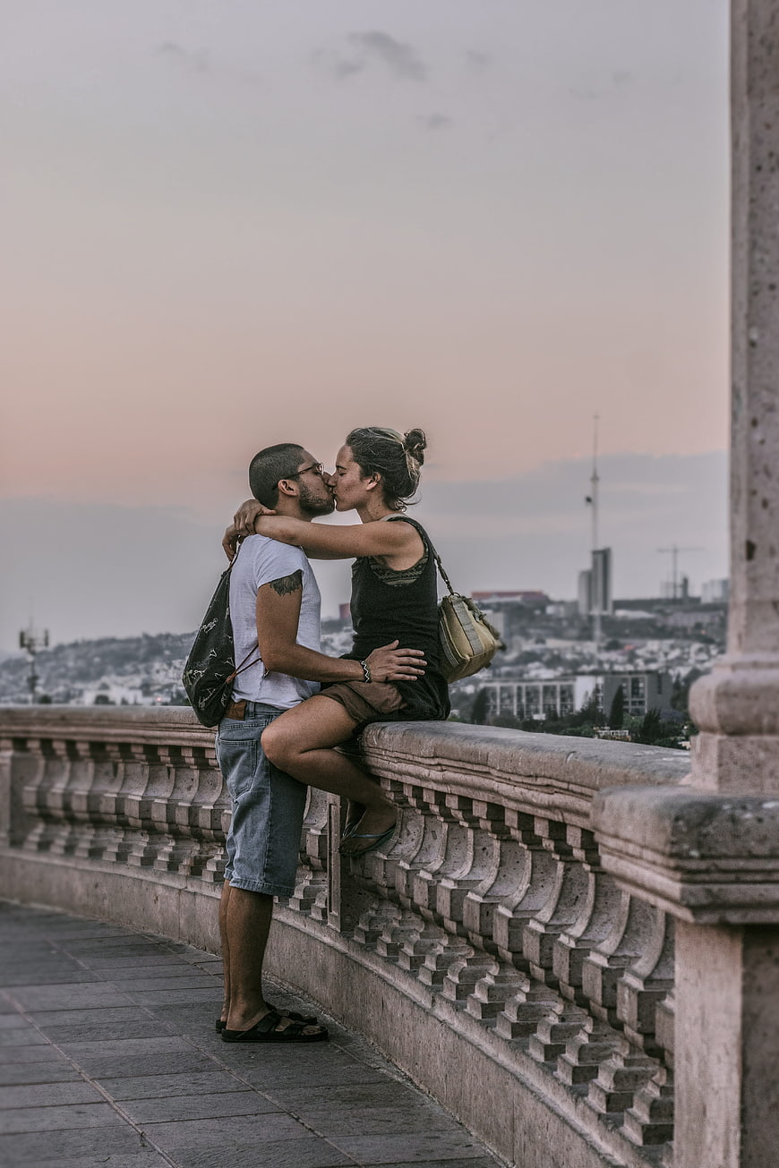 Romantic couple kissing on a stone bridge at sunset