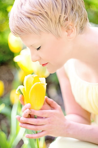 Young woman smelling yellow tulip in spring garden