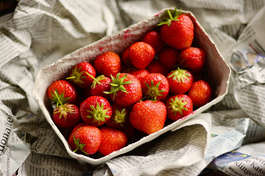 Fresh Red Strawberries in a Cardboard Box on Newspaper