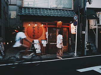 Motion blur cyclist passing traditional Japanese restaurant street