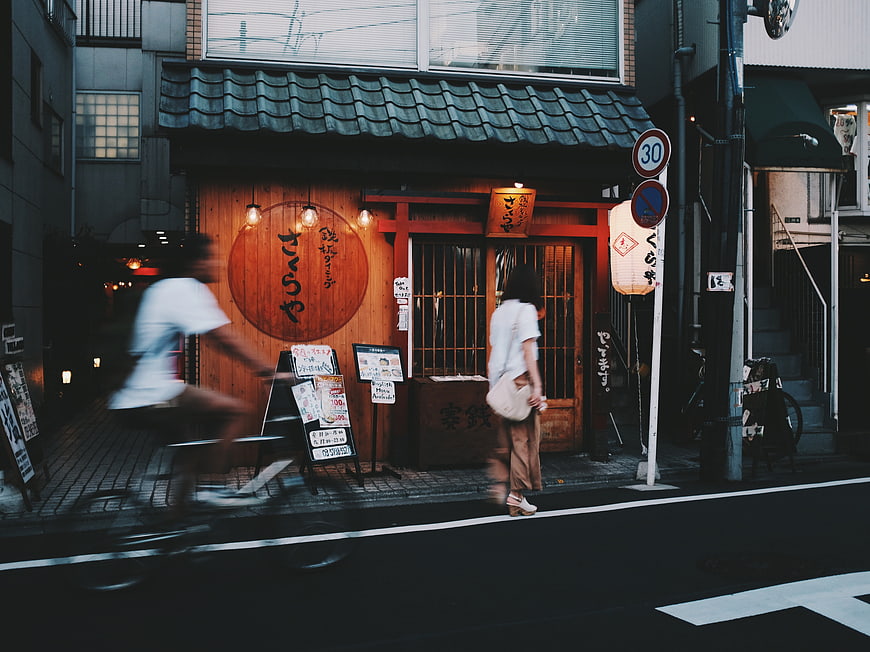 Motion blur cyclist passing traditional Japanese restaurant street