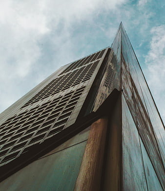Low angle view of modern skyscraper against cloudy sky