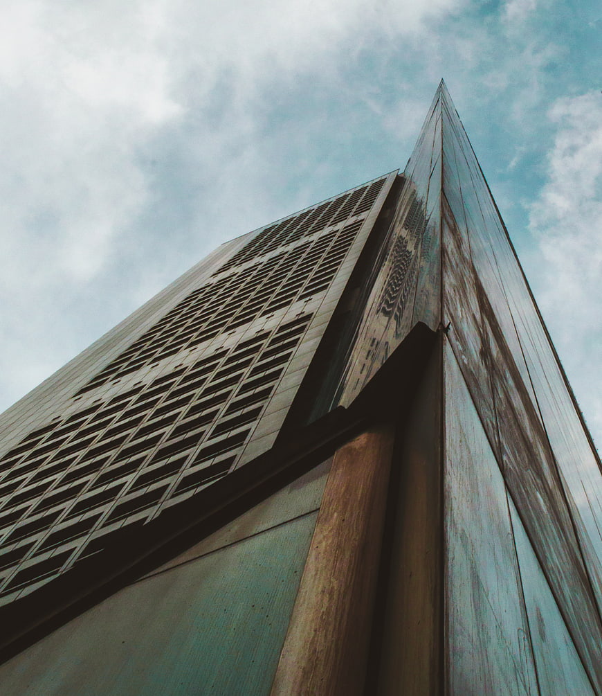 Low angle view of modern skyscraper against cloudy sky