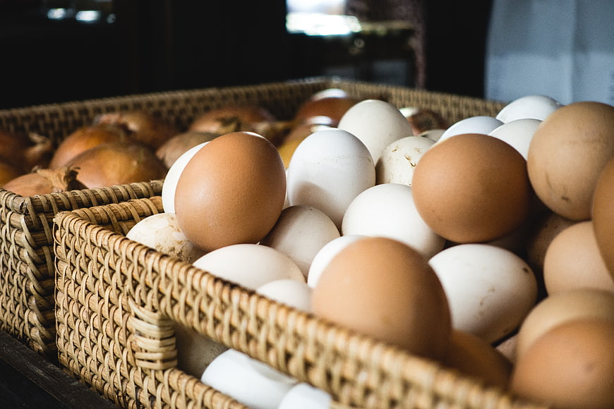 Fresh brown and white eggs in woven baskets