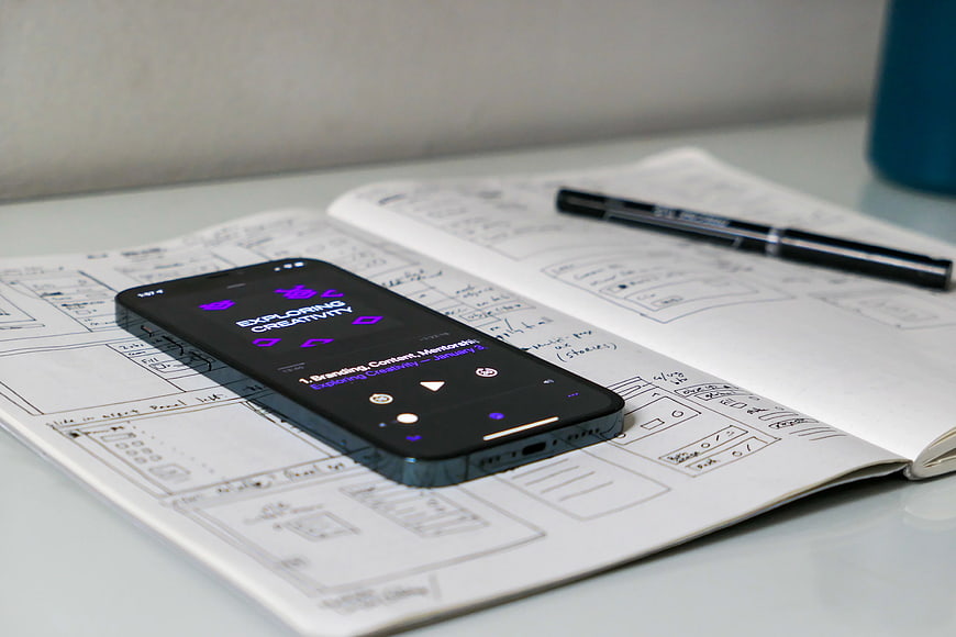 Smartphone on Sketchbook with UI Wireframes and Pen