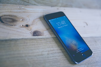 Smartphone on rustic wooden table with blue screen