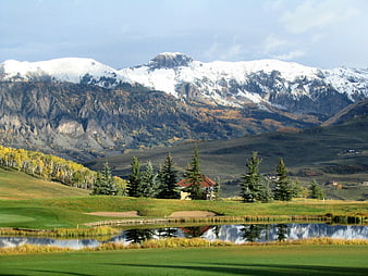 Scenic Golf Course with Snow-Capped Mountains and Pond Reflection