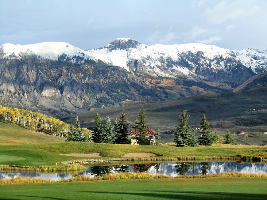 Scenic Golf Course with Snow-Capped Mountains and Pond Reflection