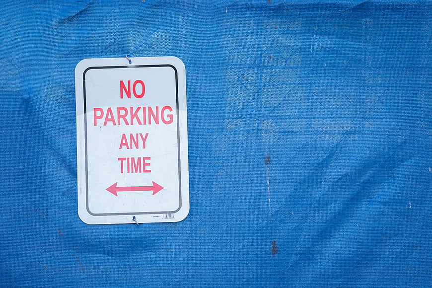 No Parking Any Time Sign on Blue Tarp Background