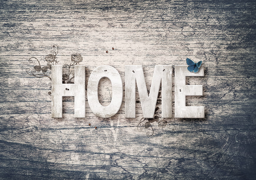 Vintage wooden HOME letters on rustic background with blue butterfly