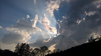 Dramatic sun rays breaking through clouds over silhouetted hills