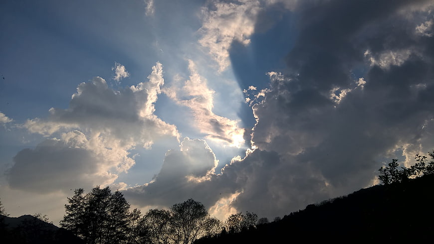 Dramatic sun rays breaking through clouds over silhouetted hills