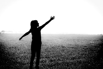 Silhouette of Girl with Arms Raised in Field