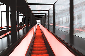 Modern red escalator in glass enclosed architectural tunnel