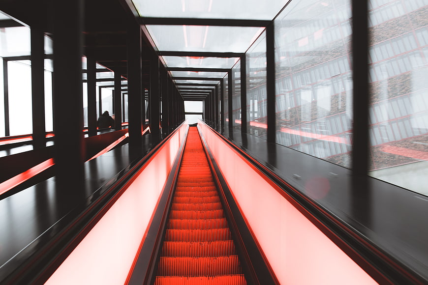 Modern red escalator in glass enclosed architectural tunnel