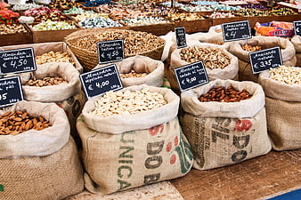 Burlap sacks of assorted nuts with handwritten price tags at a local market