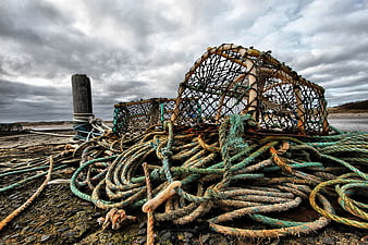 Weathered Crab Pots and Ropes on Rocky Shore Under Dramatic Sky