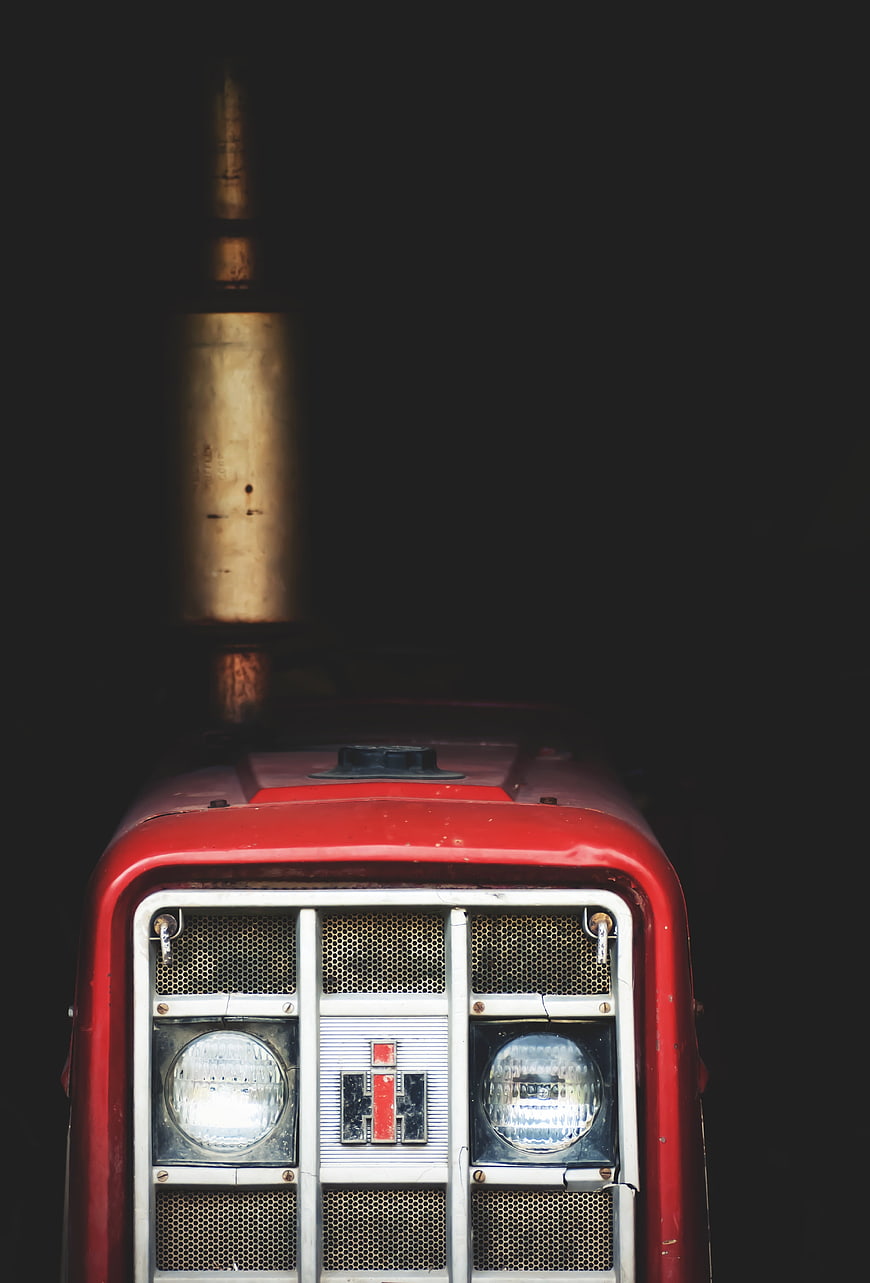 Close-up of vintage red tractor front grille and headlights