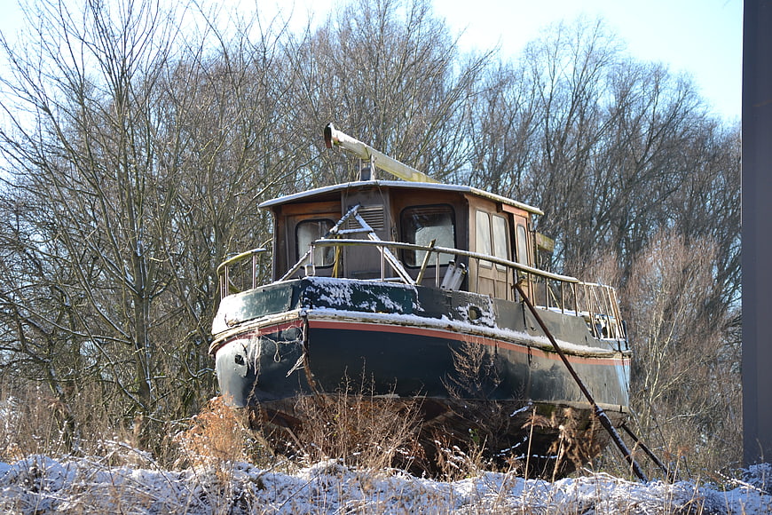 Abandoned rusty boat in snowy winter forest