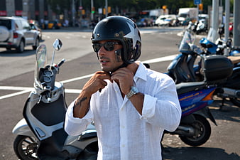 Man in White Shirt Adjusting Motorcycle Helmet on Street