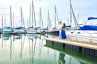 Couple Standing on Dock in Marina with Sailboats