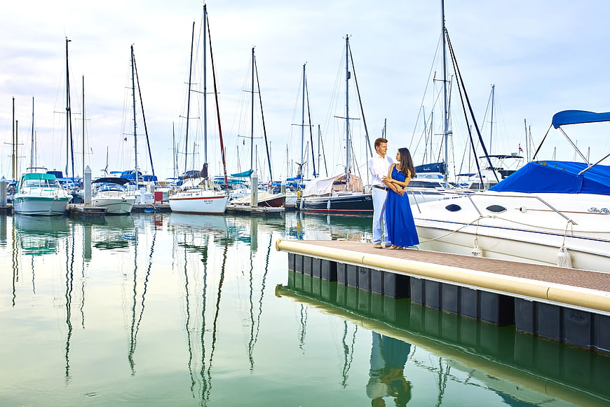 Couple Standing on Dock in Marina with Sailboats
