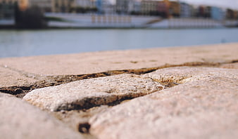 Close-up of textured stone pavement by a waterfront