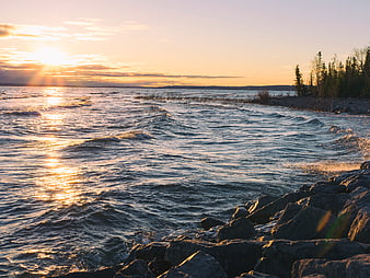 Golden Sunset Over Rocky Coastline with Gentle Waves