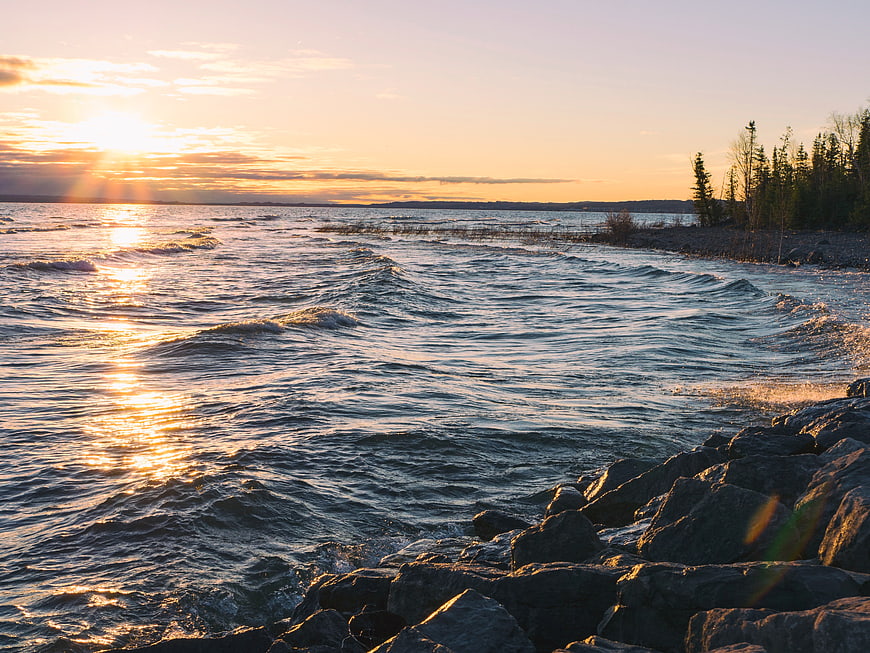 Golden Sunset Over Rocky Coastline with Gentle Waves