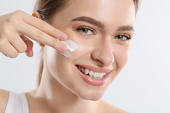 Woman applying cream to face for skincare routine