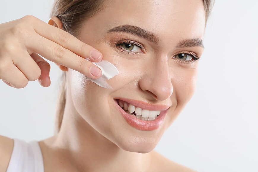 Woman applying cream to face for skincare routine