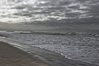 Moody Overcast Beach Scene with Rolling Waves and Gray Sky